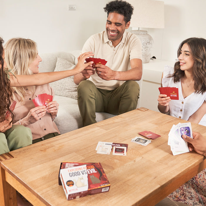 Three friends playing Exploding Kittens Good vs Evil at a table