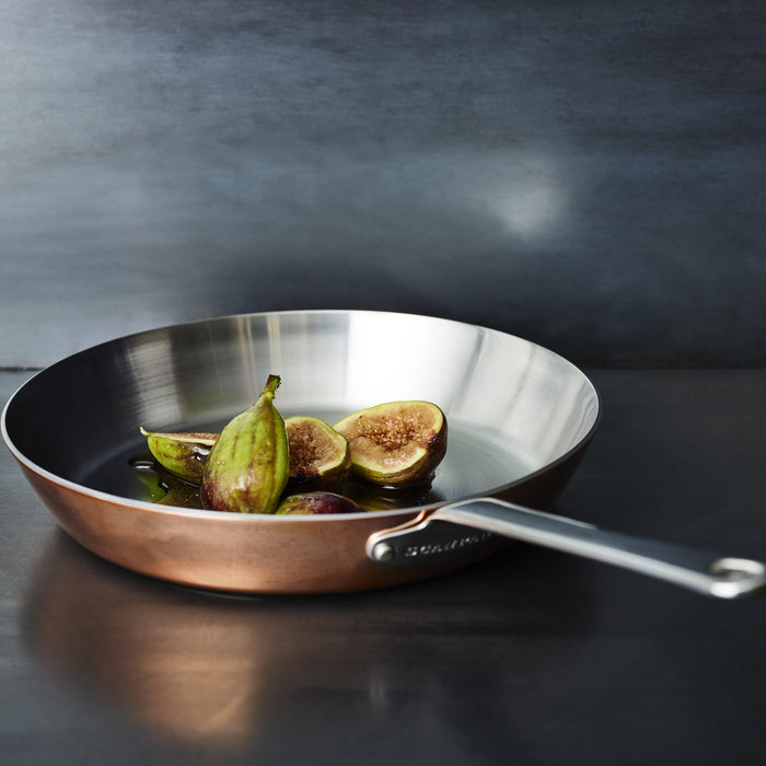 Copper frying pan with figs on a dark surface
