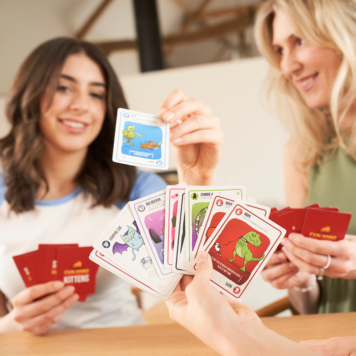 Friends holding cards while playing Zombie Kittens