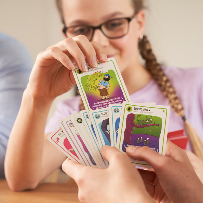 Girl holding a hand of Zombie Kittens cards